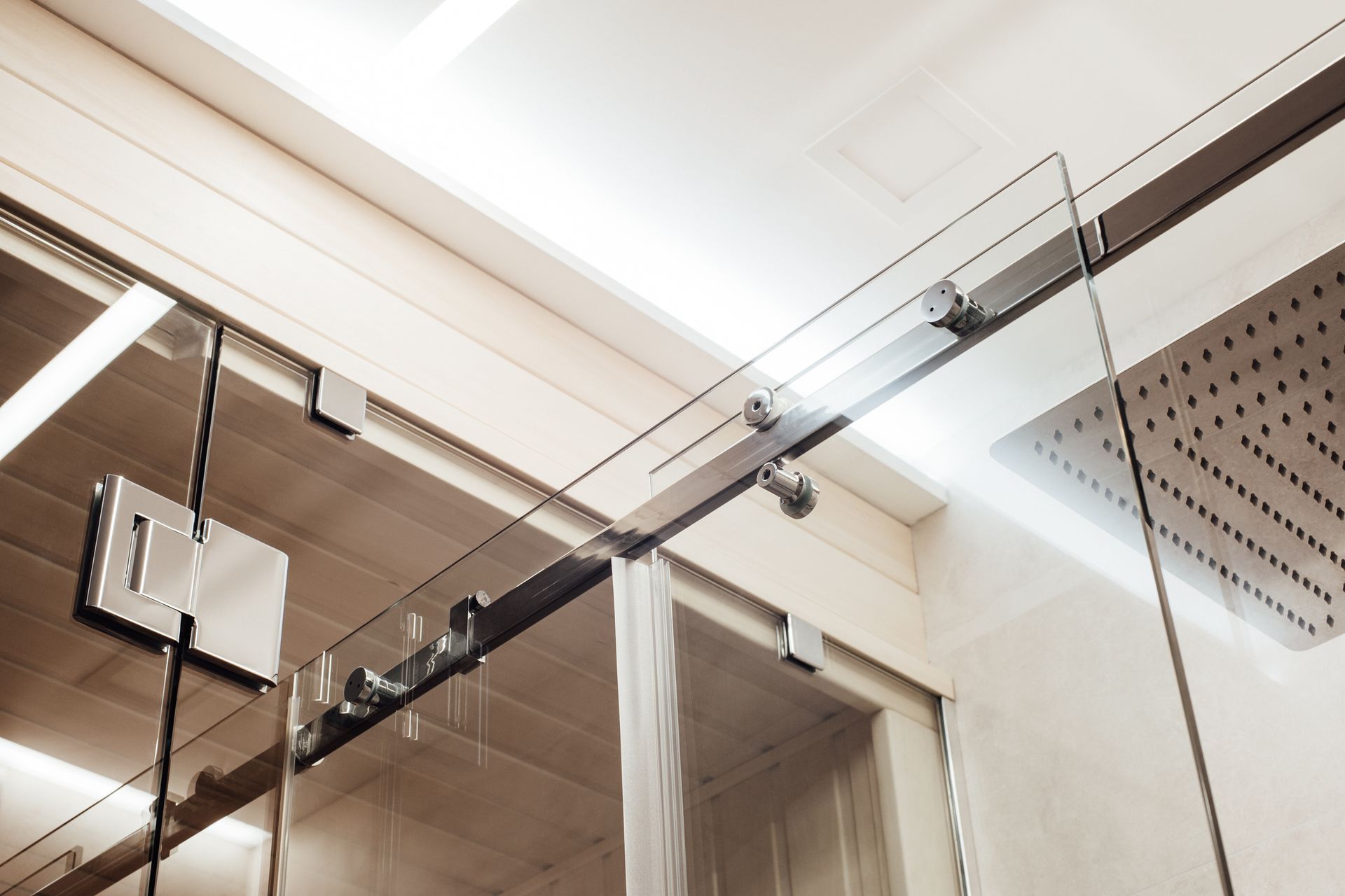 Glass shower door with metal sliding hardware and overhead track.