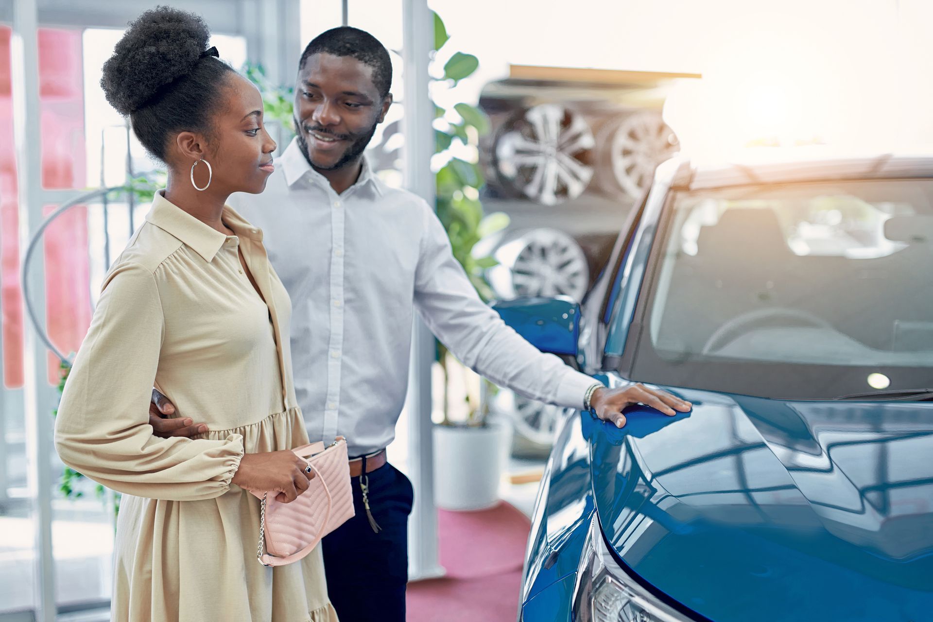 Couple looking at a blue car in a car dealership.