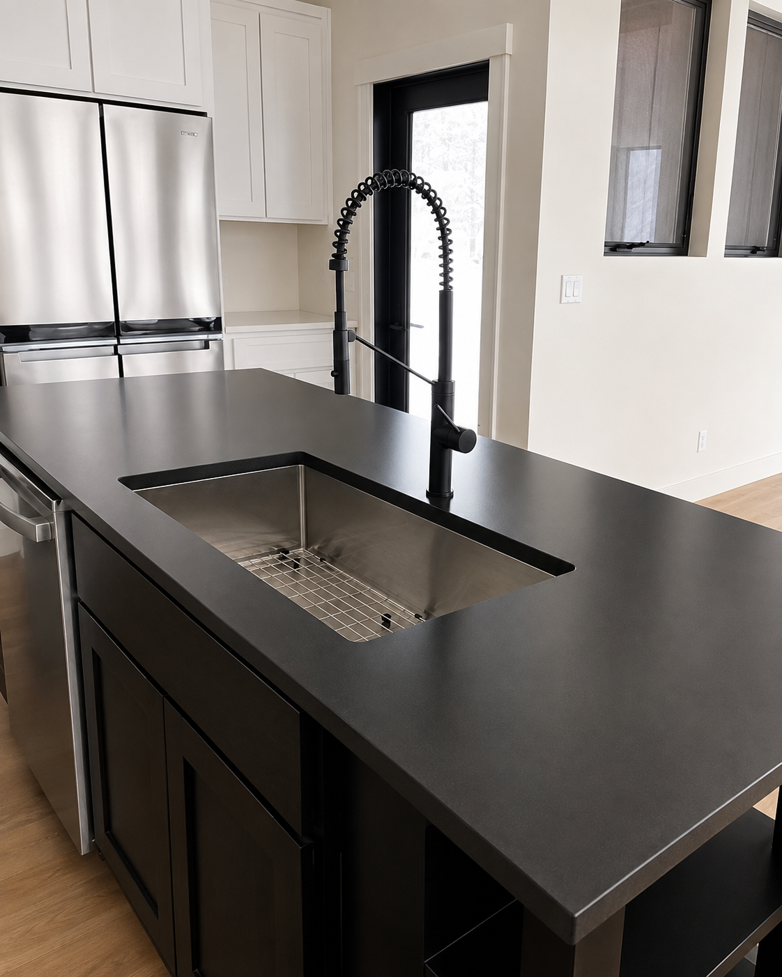 Modern kitchen island with black countertop, built-in sink, and tall black faucet in a bright room