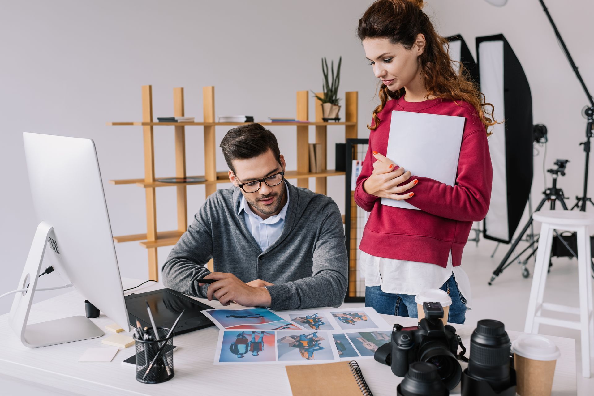 Two people reviewing print designs at a desk in a bright creative studio