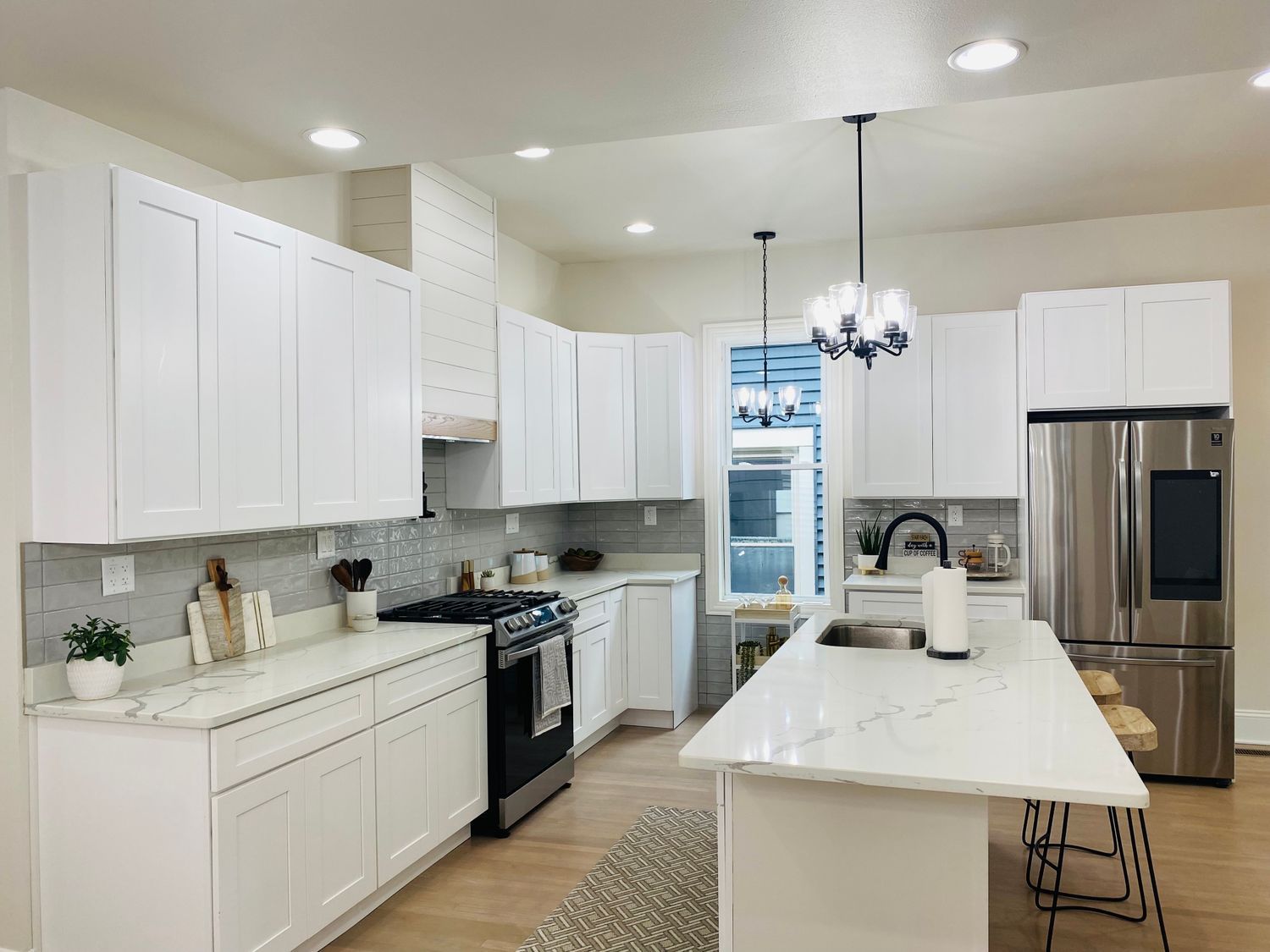 Bright modern white kitchen with island, stainless steel appliances, and pendant lights
