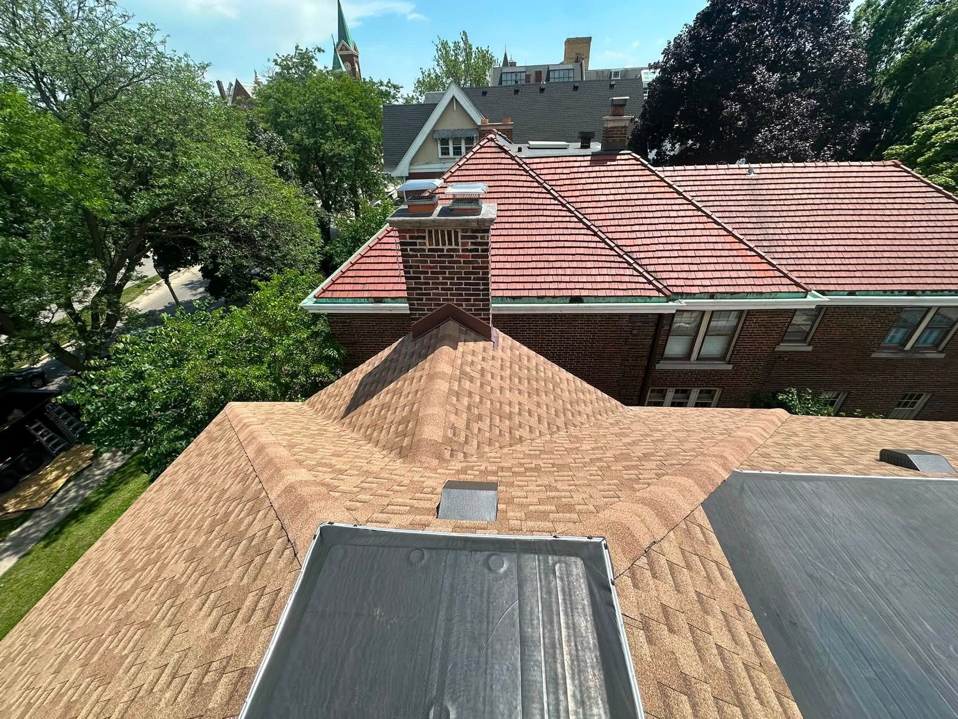 Rooftop view of red-tiled houses and green trees on a sunny day