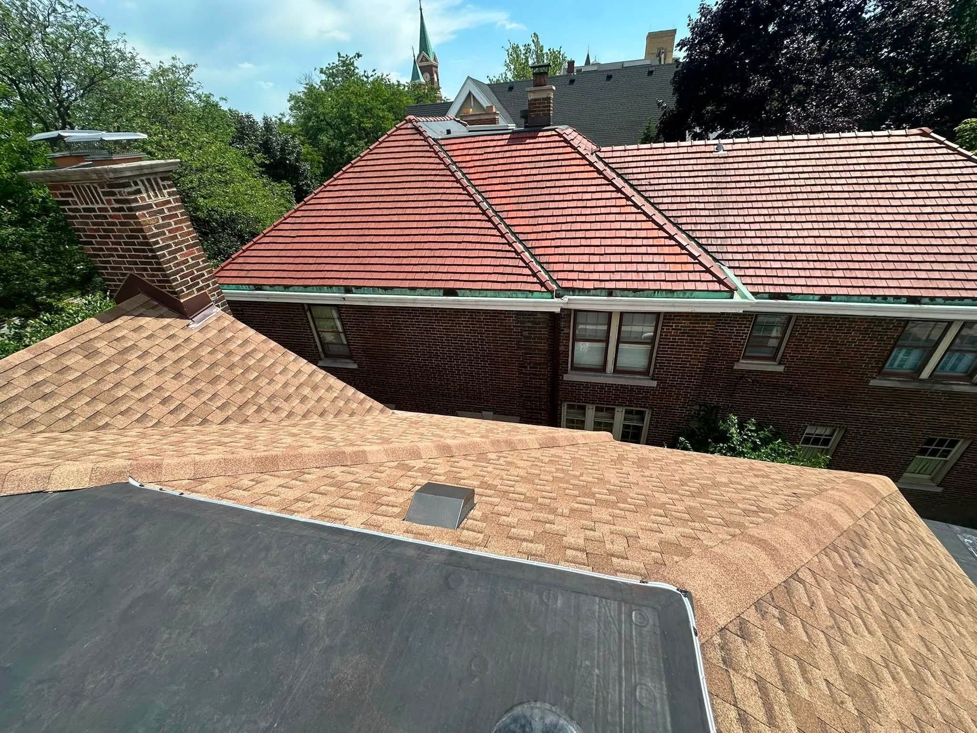 Rooftops with tan shingles and red tile roofs around a central courtyard in bright daylight