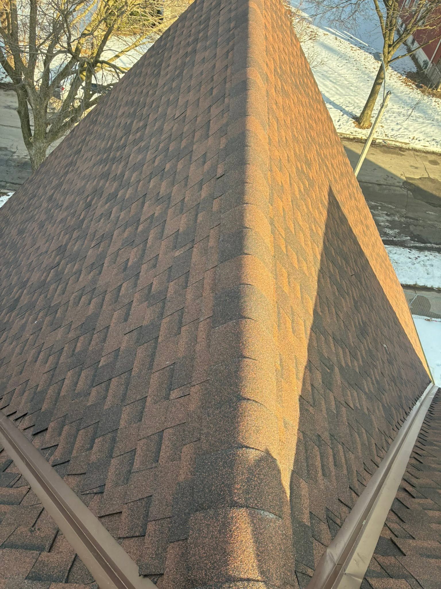 Brown shingled pyramid roof on a structure, viewed from below in daylight