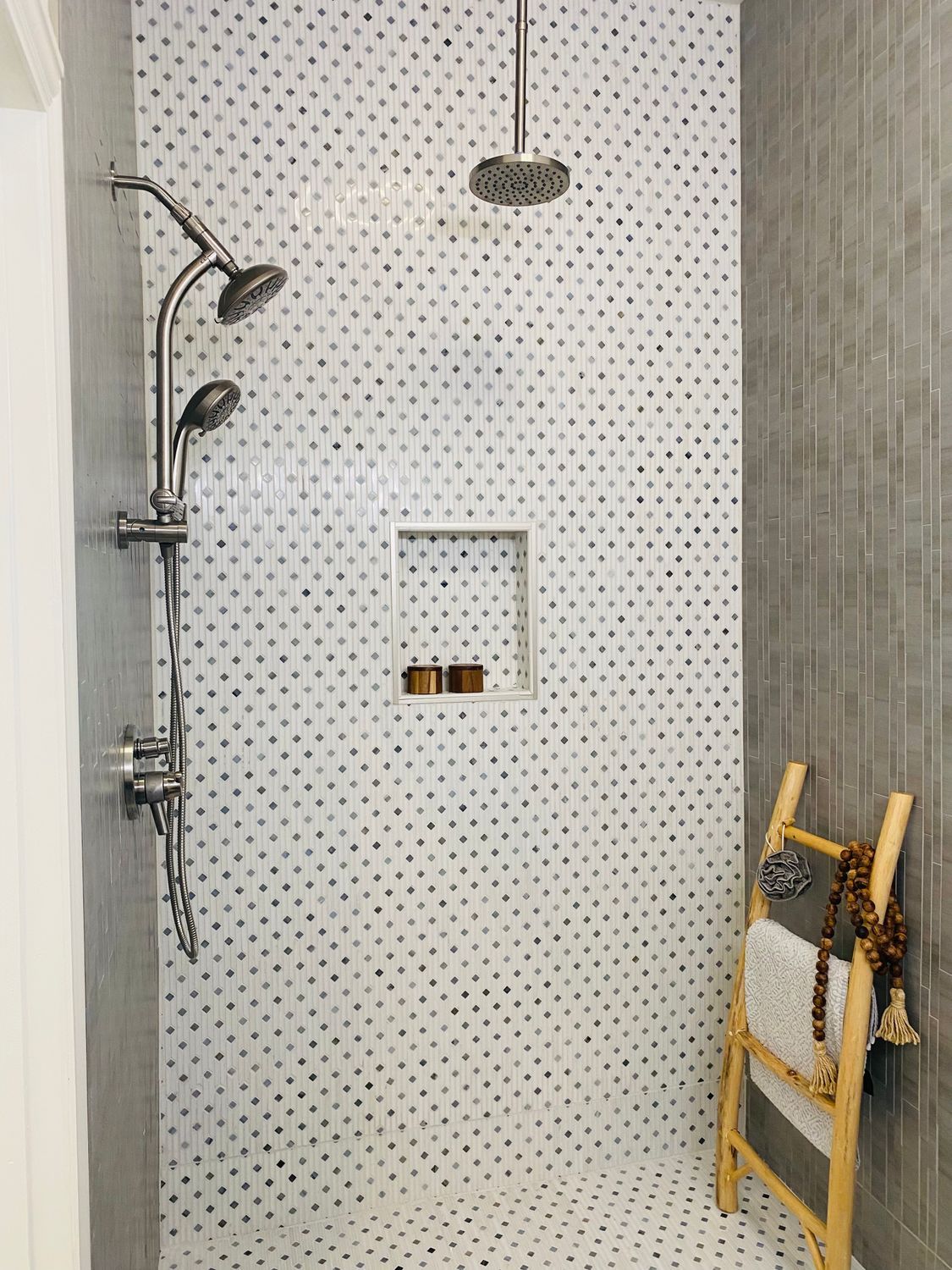 Modern shower with tiled wall, rain showerhead, handheld sprayer, and built-in shelf niches