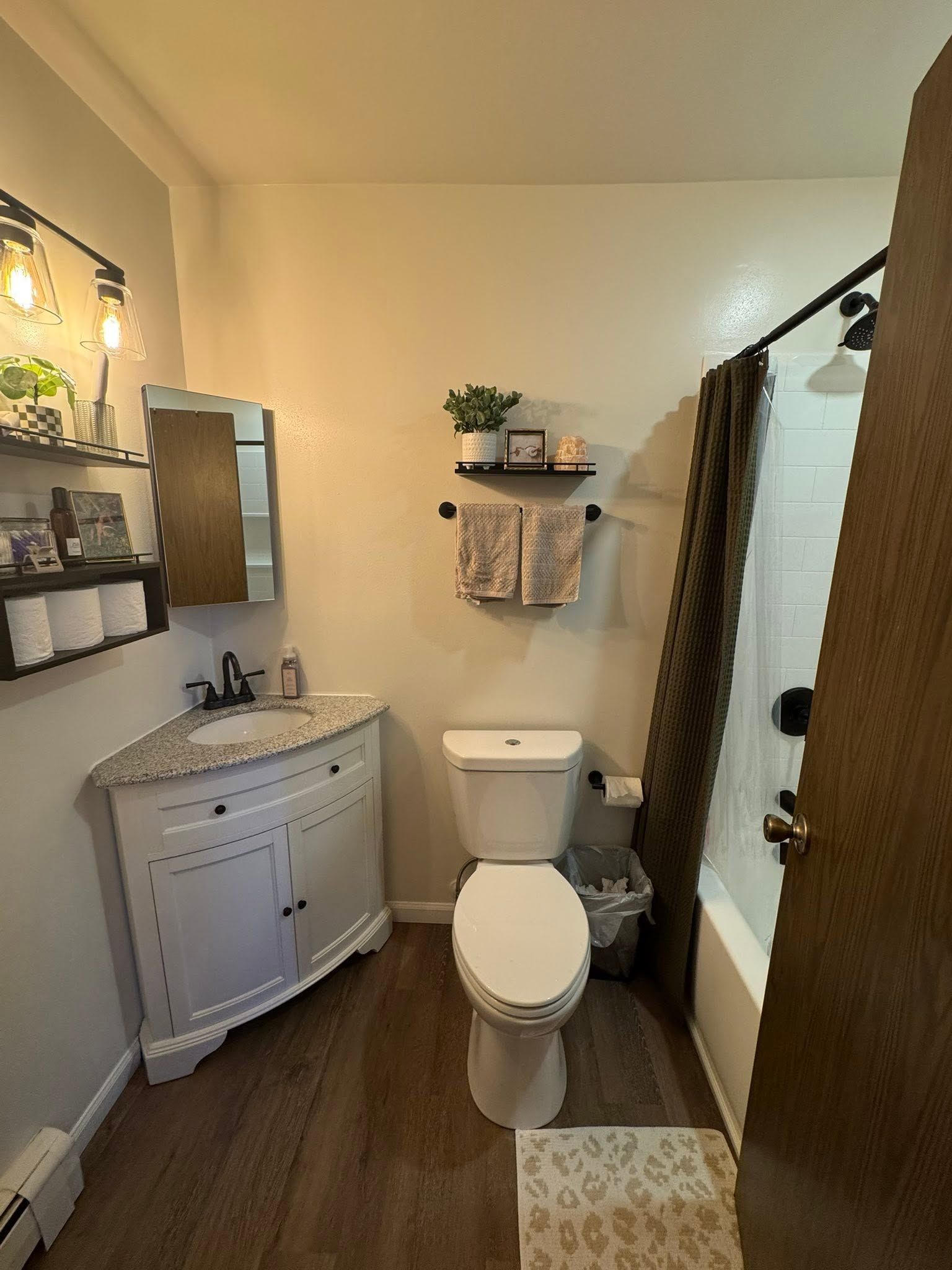 Small bathroom with white vanity, toilet, shower, and brown curtain.
