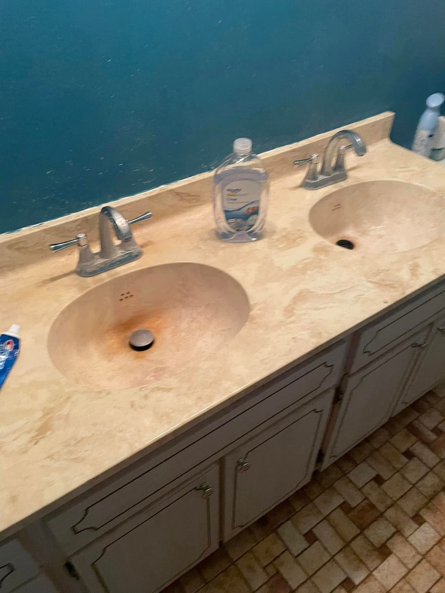 Double-sink bathroom vanity with beige countertop, soap dispenser, and blue wall.
