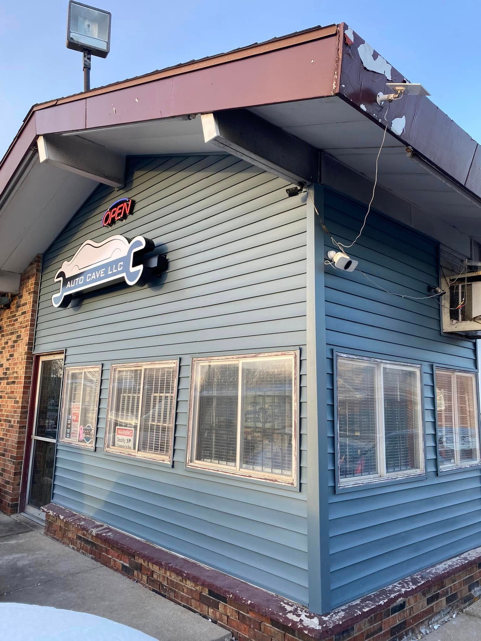 Blue-gray corner storefront with awning and sign, viewed from outside under a clear sky