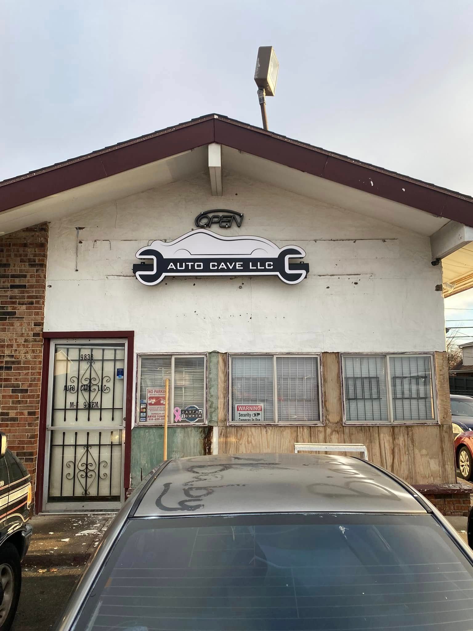 Exterior of an auto repair shop with a wrench sign and a parked car in front