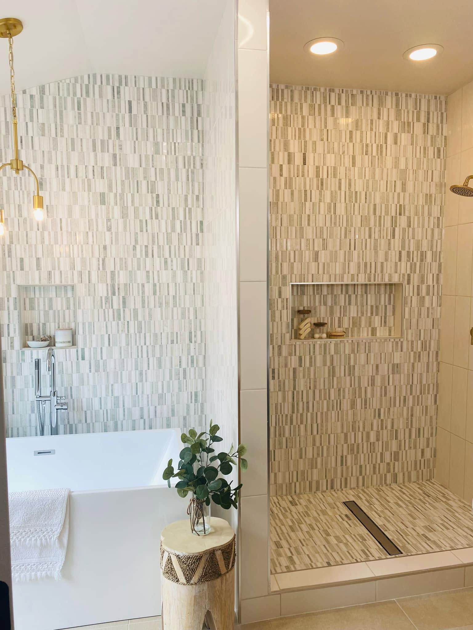 Bathroom with a white tub and mosaic-tiled walk-in shower lit by recessed lights