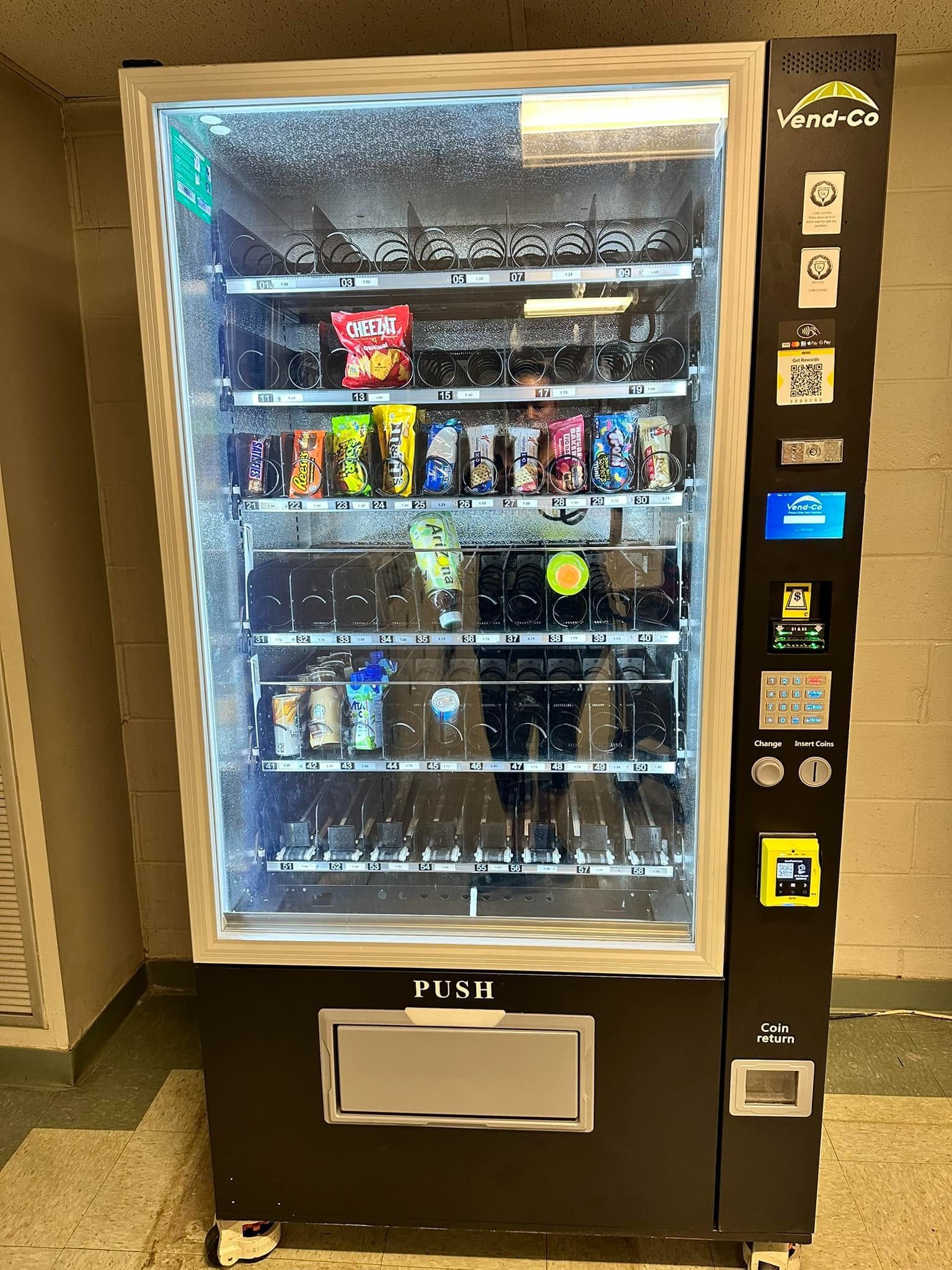 Snack vending machine with illuminated glass front and assorted drinks and chips inside