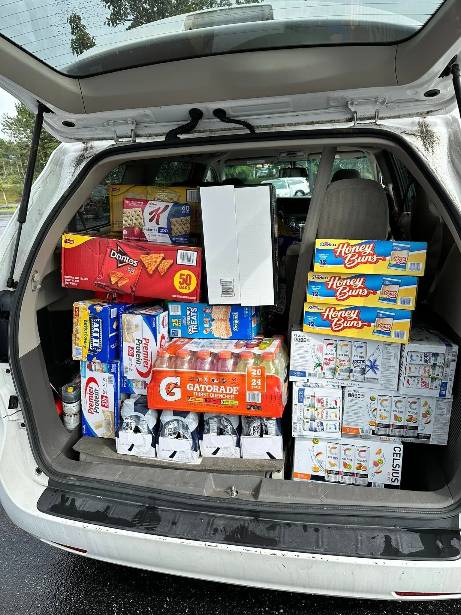 SUV trunk packed with stacked cases and boxes of assorted goods, including colorful cereal and food cartons