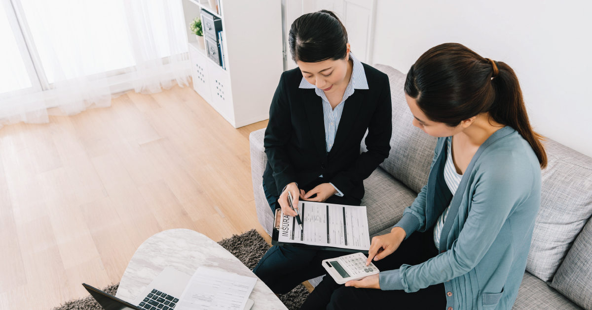 Two people reviewing documents together on a couch in a bright living room