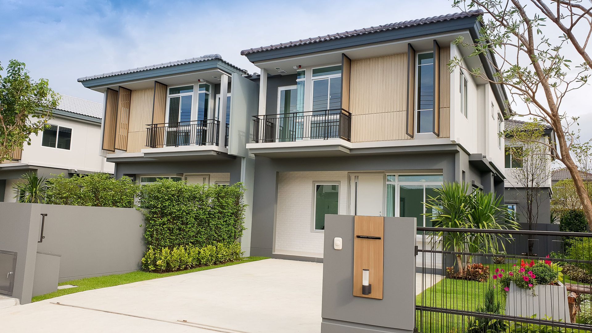Modern two-story house with balcony, beige curtains, and a gated driveway