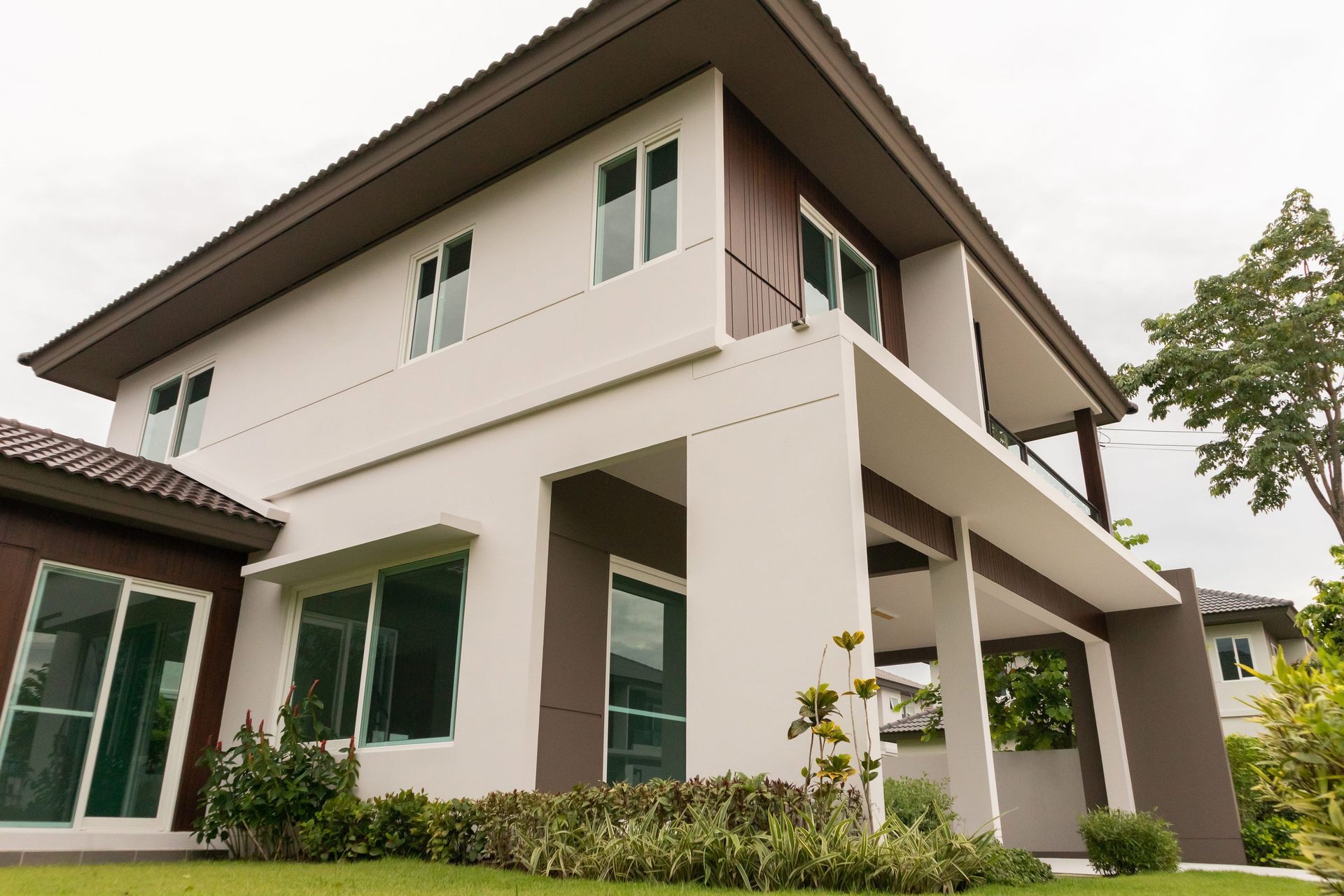 Modern white two-story house with green-trimmed windows and a covered porch, viewed from the lawn.