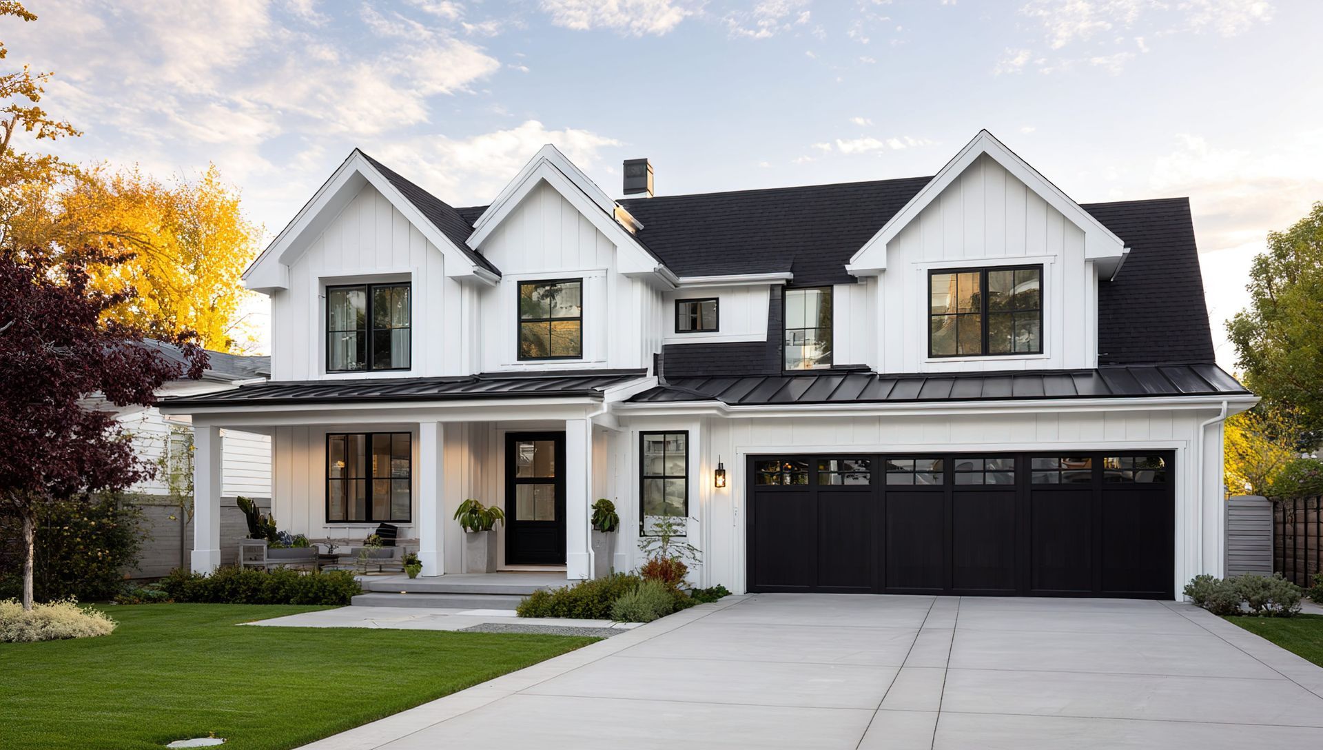 Modern white two-story house with black trim, a two-car garage, and a front lawn at dusk