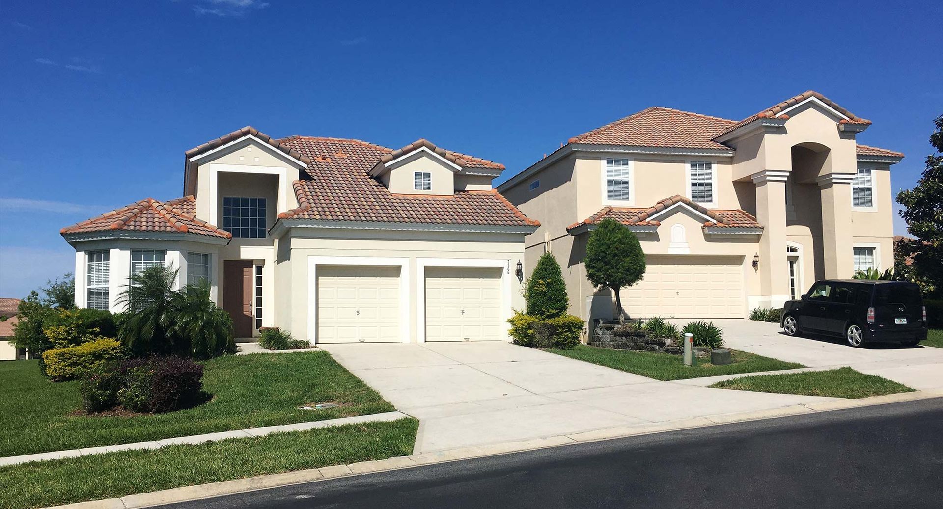 Suburban house with stucco exterior, red-tile roof, and driveway in a landscaped neighborhood