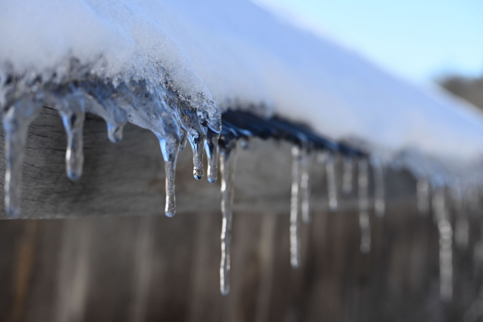Icicles hanging from a roof edge after a snow and ice storm