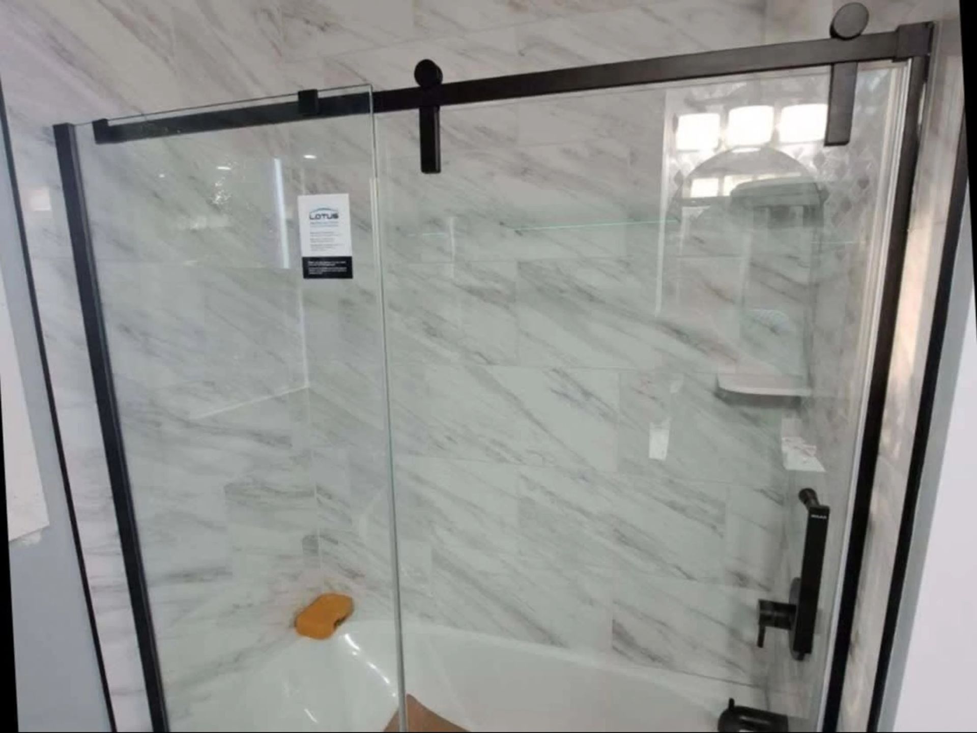 Glass shower enclosure with dark hardware and white marble tile walls