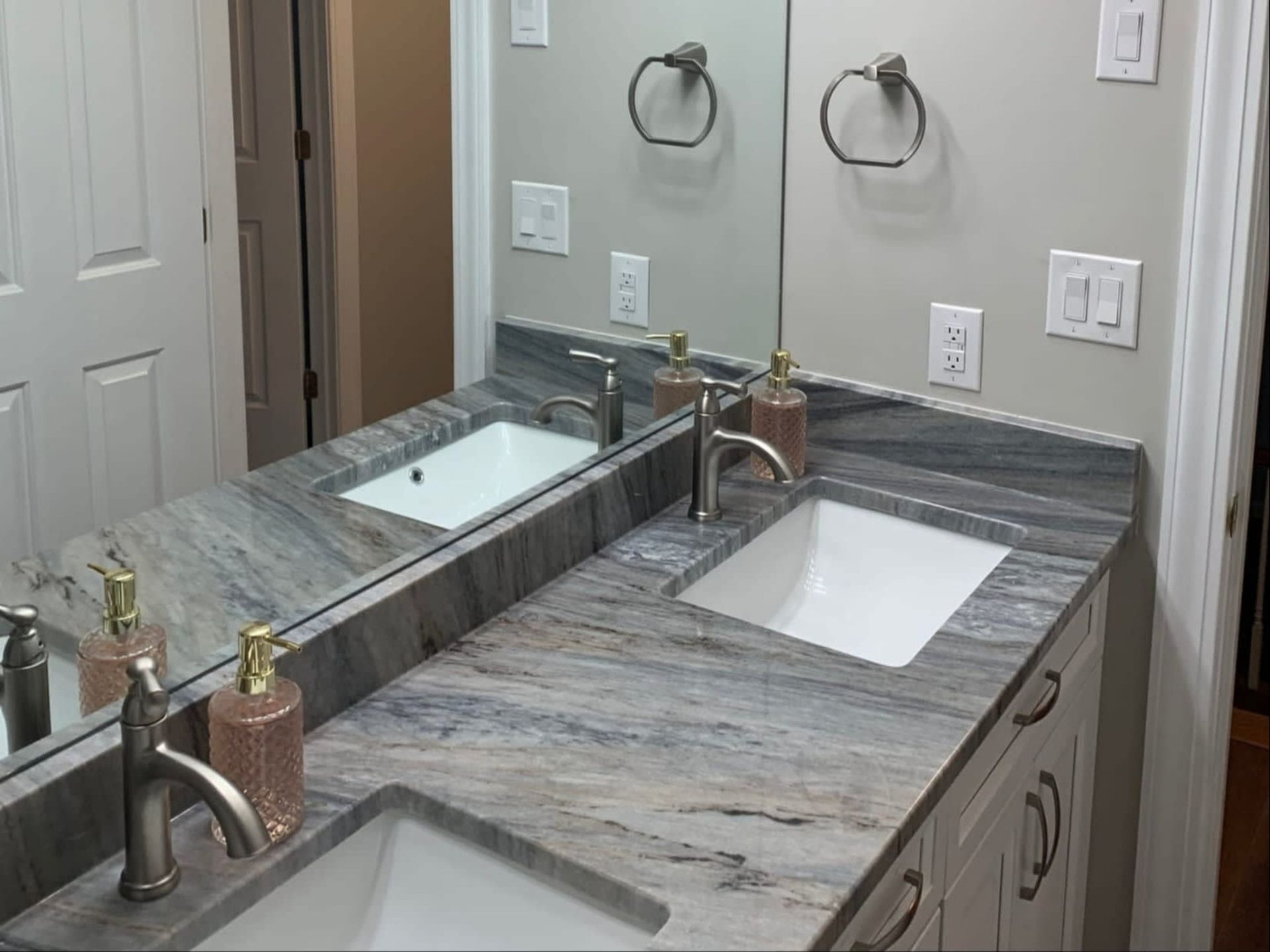 Bathroom vanity with double sinks, marble countertop, mirror, and chrome faucets