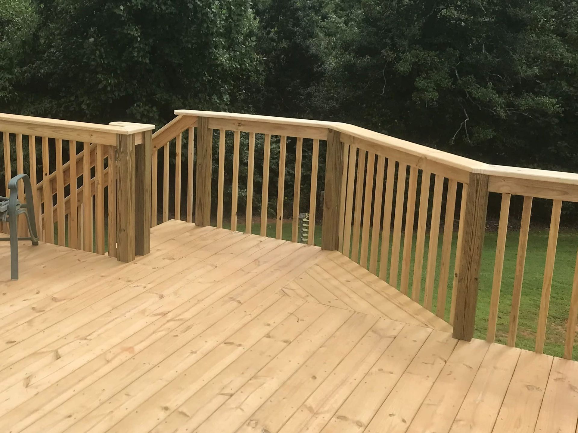 Wooden deck with railings overlooking a wooded yard