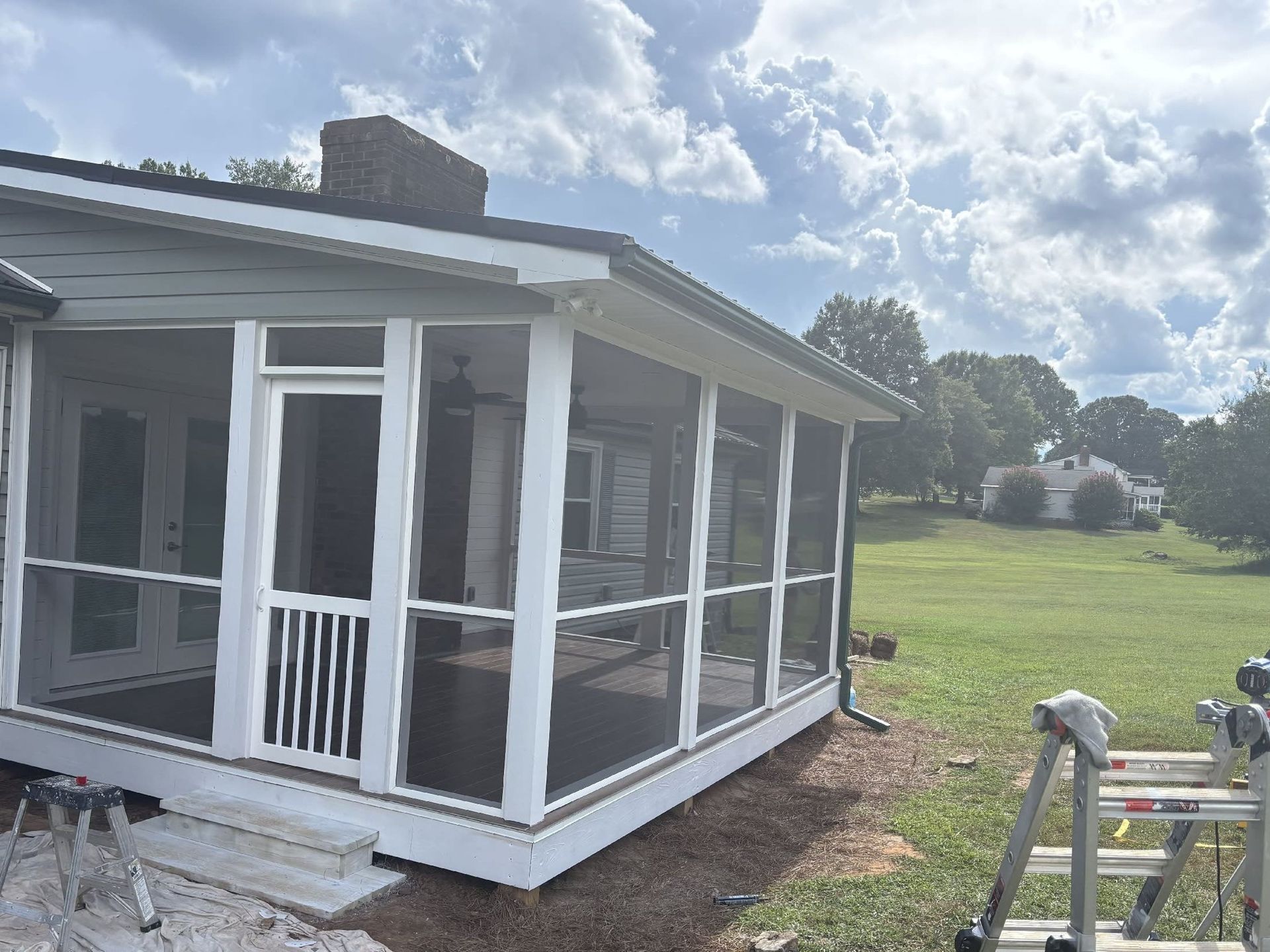 Screened porch addition on a house under construction, with white trim and a grassy yard.