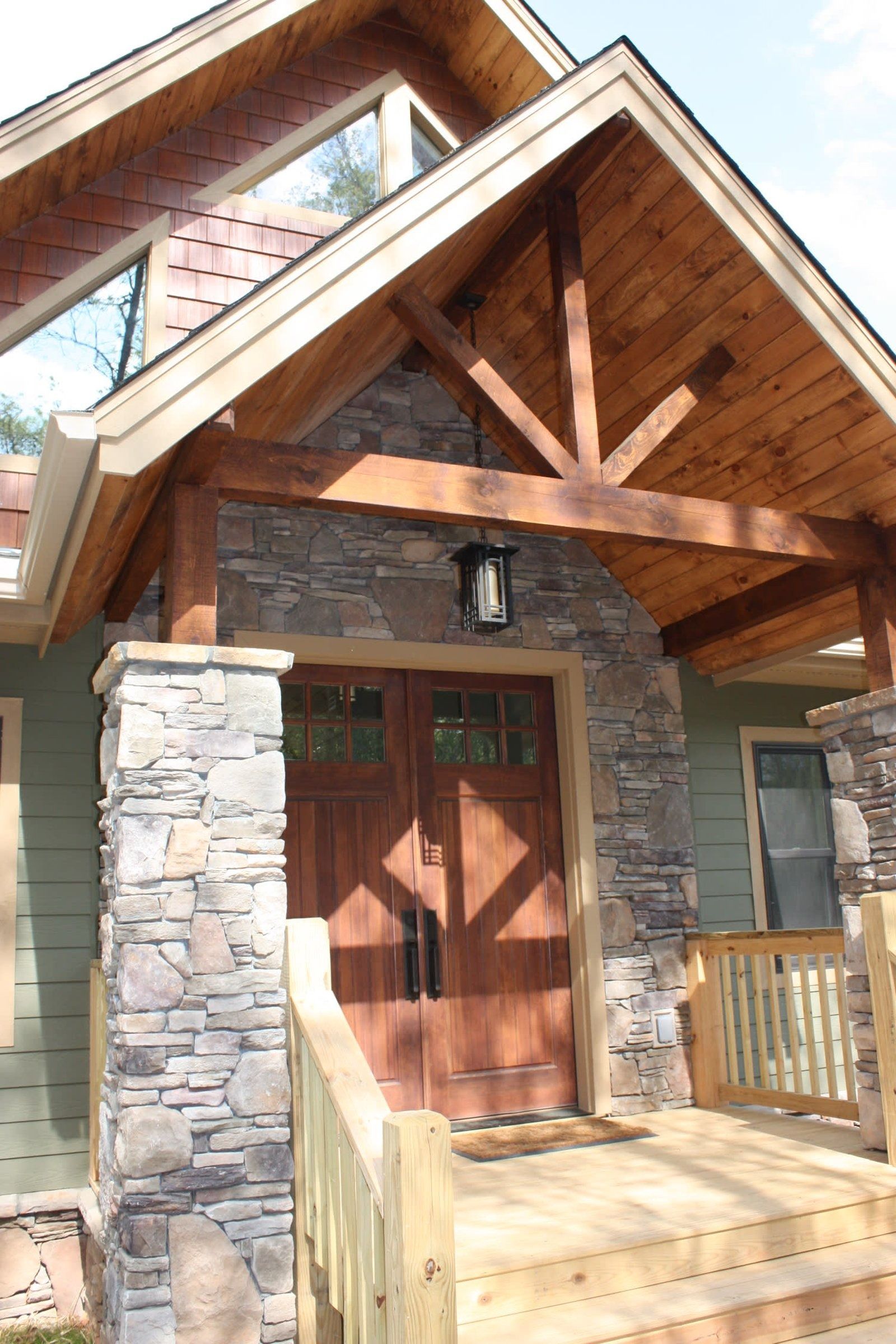 Rustic stone and wood house entrance with a peaked roof and double wooden doors