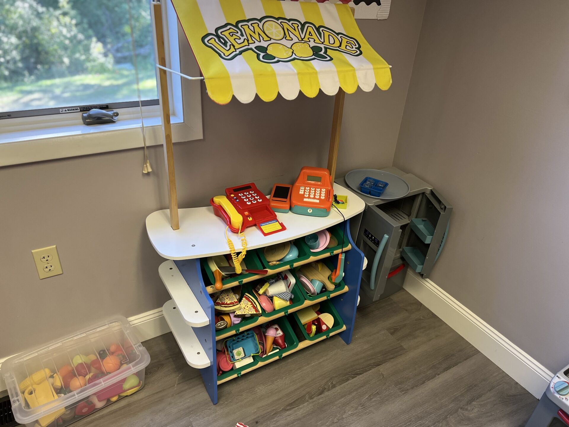 A toy store with a yellow and white awning is sitting in a room.