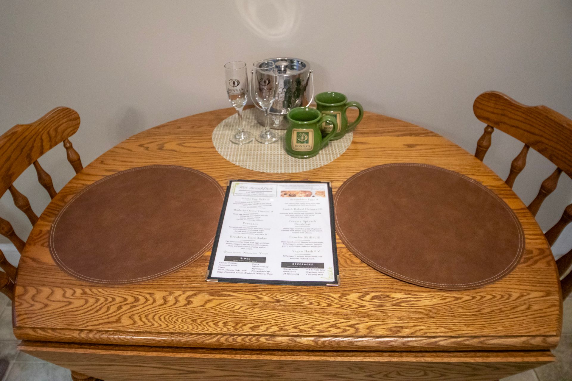 Wooden table set for two with placemats, menu, and mugs.