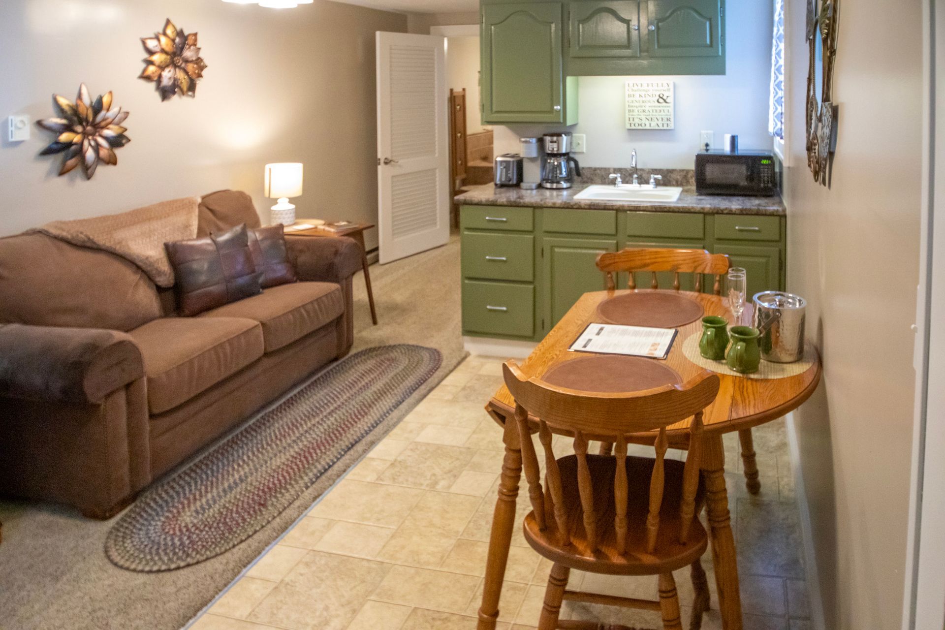 Cozy studio apartment with a brown sofa, small kitchen, and a wooden table with chairs.