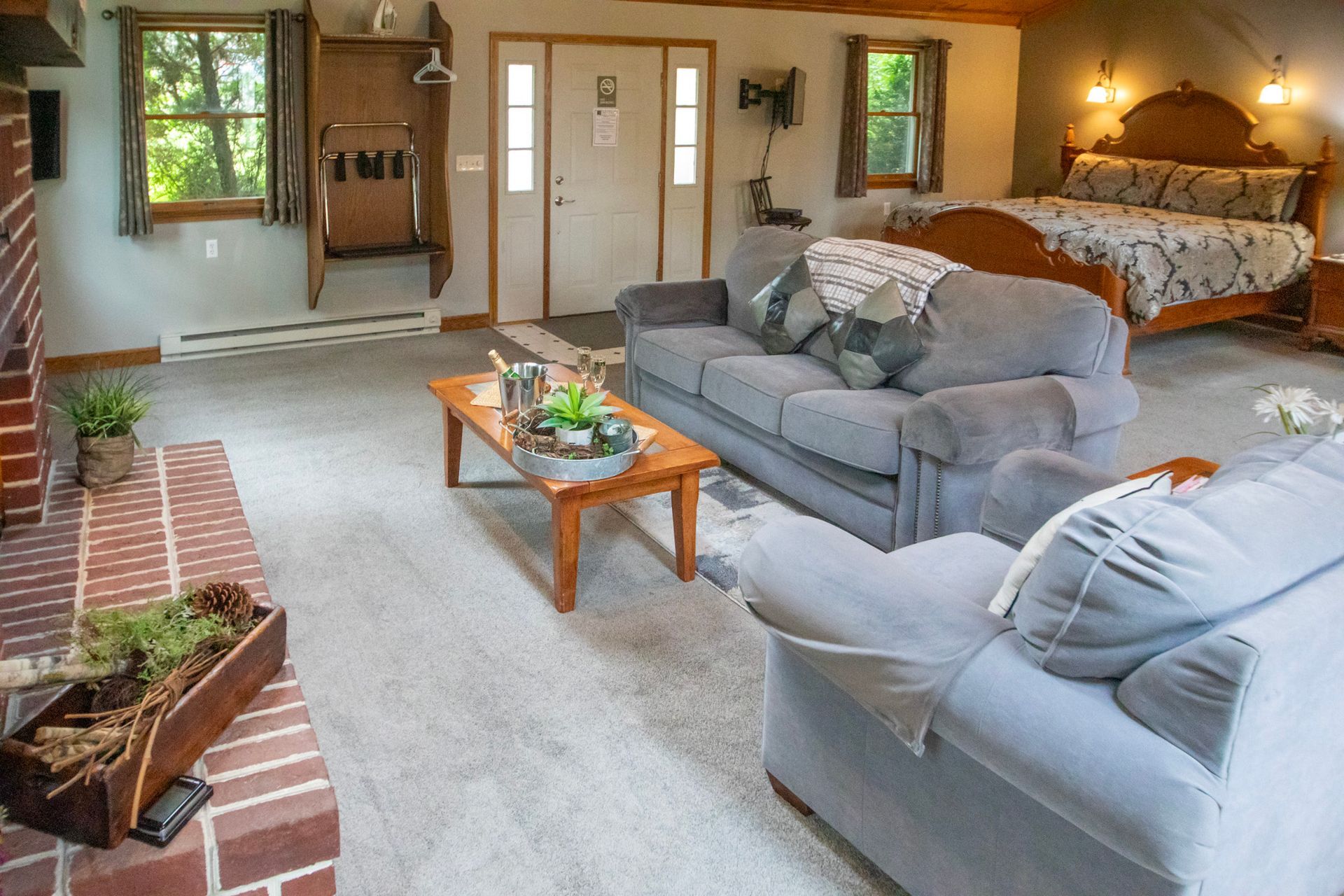 Open-concept living space with a bed, couch, fireplace, and entry doors.