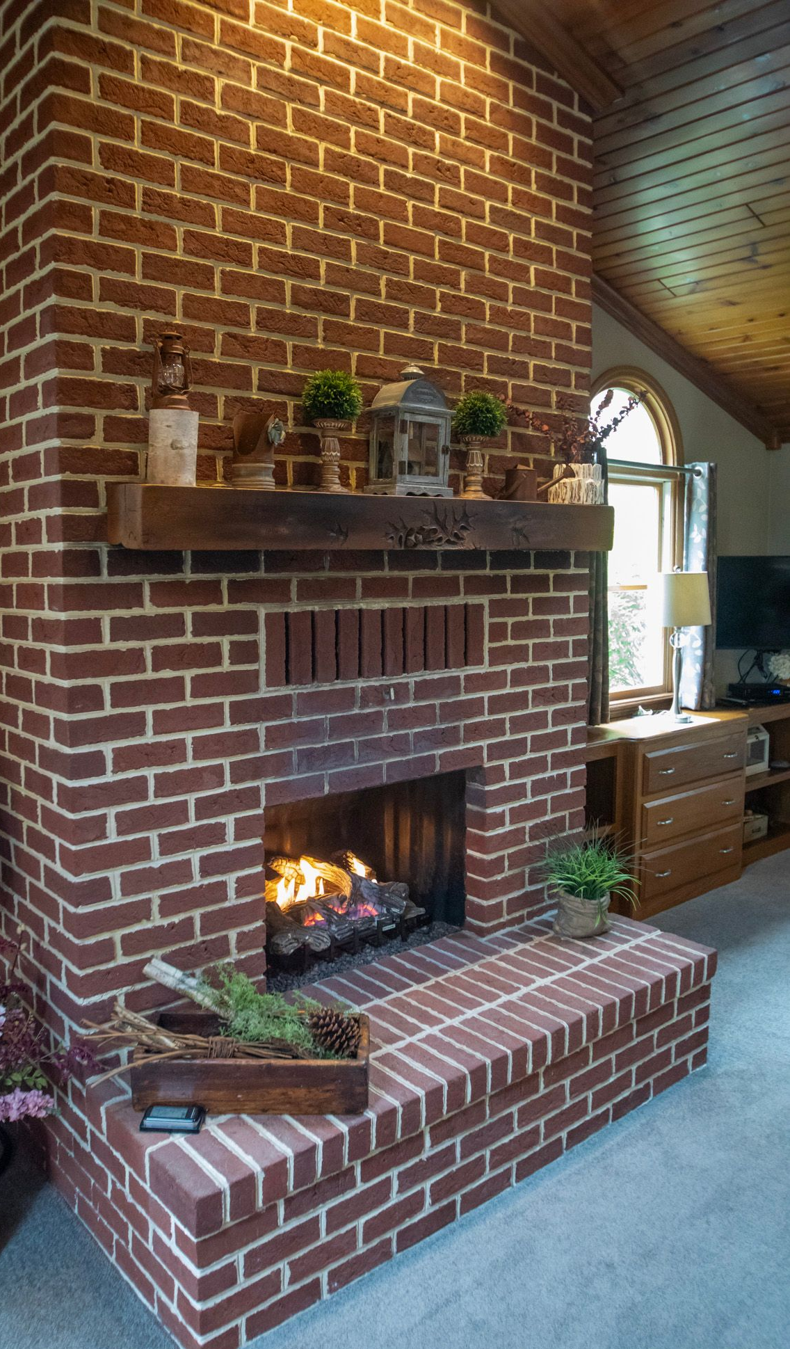 Brick fireplace with a wooden mantle and burning fire.