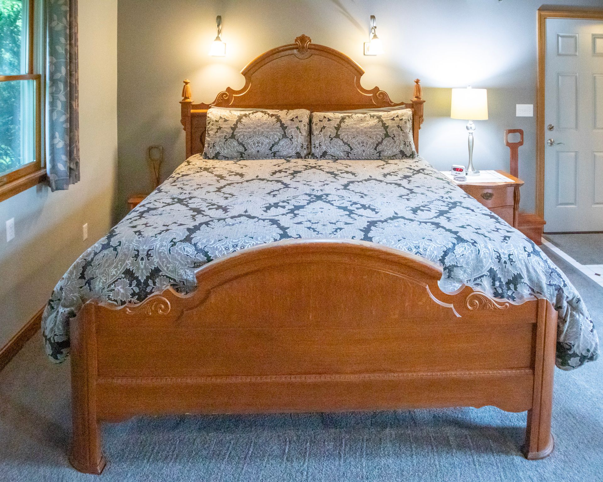Bedroom with wooden bed, floral bedding, bedside tables, and a closed door.
