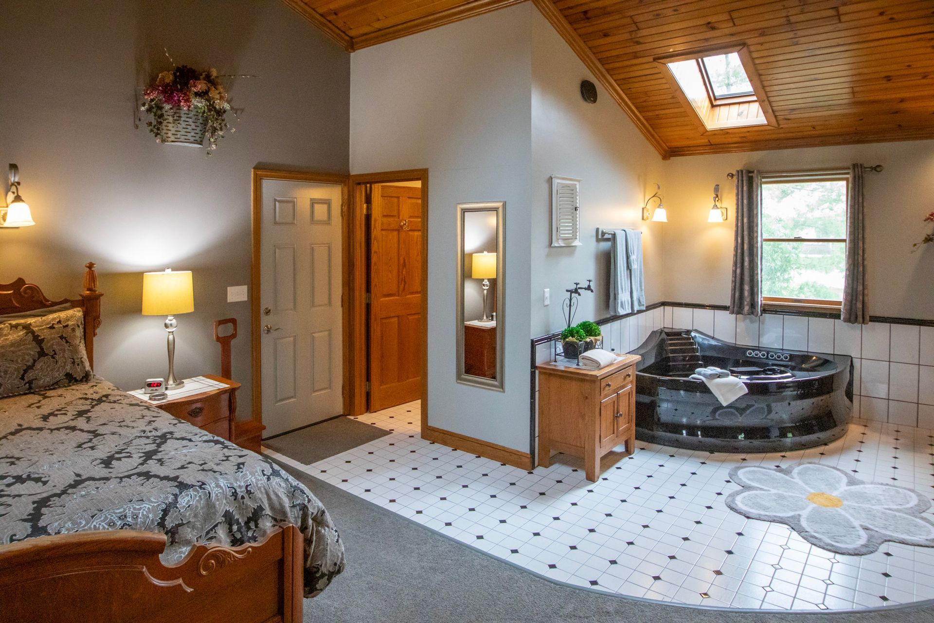 Bedroom with bed, jacuzzi, wood ceiling, skylight, and daisy tile accent.