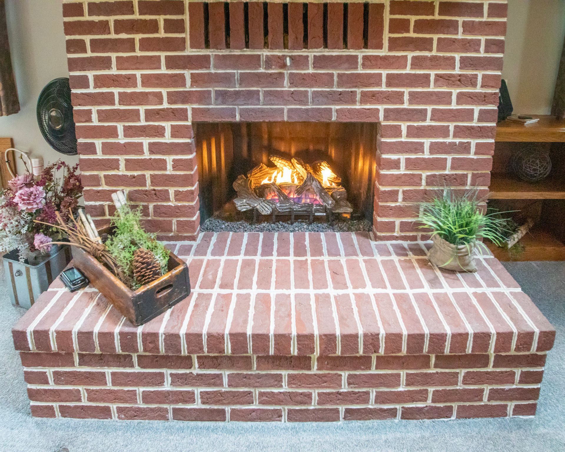 Brick fireplace with burning fire and decorative items on the hearth.