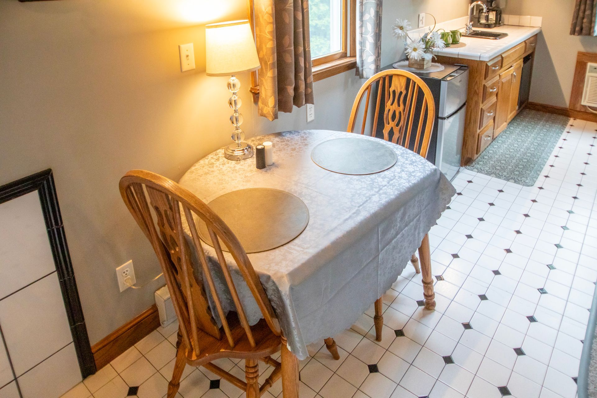 A small kitchen with a table set for two, near a window and cabinets.