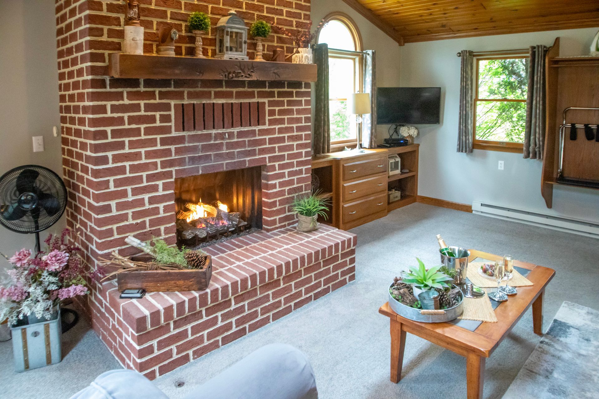 Cozy living room with brick fireplace, small coffee table, and wood ceiling.