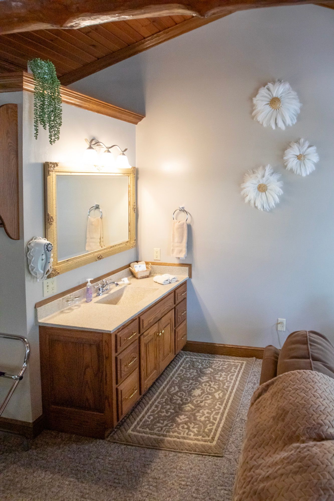 Bathroom with wood vanity, large mirror, daisy wall decorations, and a rug.
