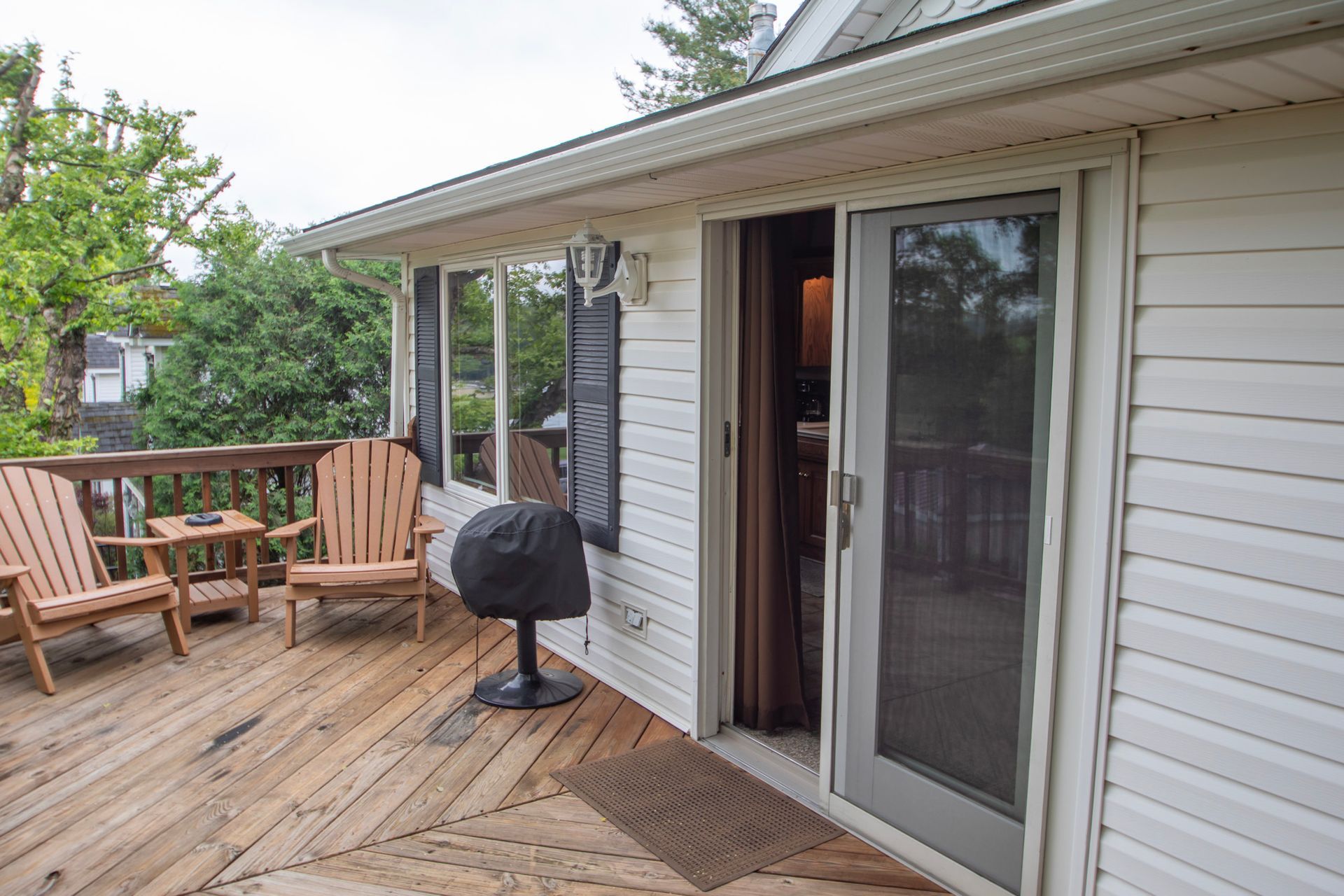 Wooden deck with two chairs, a small table, and a sliding glass door leading indoors.
