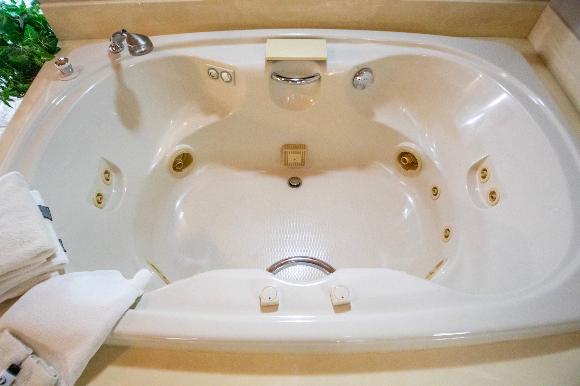 White oval jacuzzi tub with jets, faucet, and bath accessories.