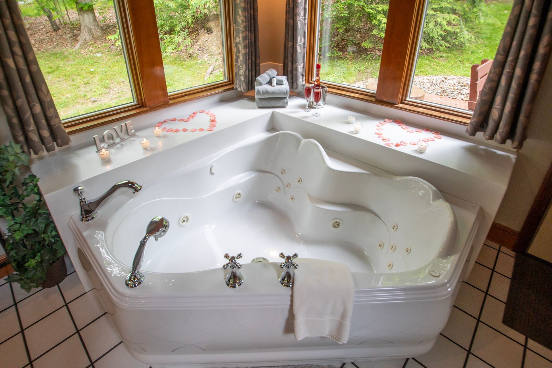 White jacuzzi tub in bathroom by a window, with a towel on edge and floral decor.