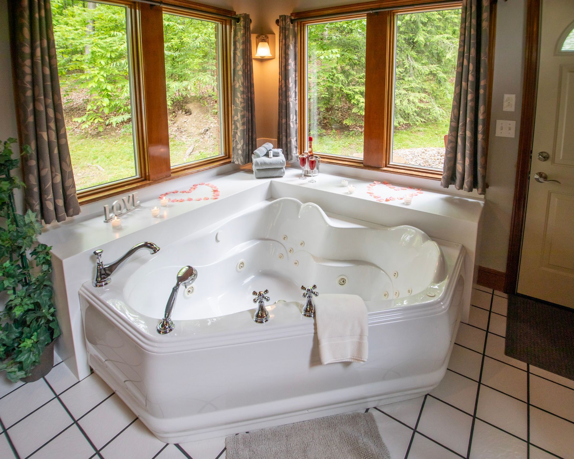 A white jacuzzi tub in a corner with large windows overlooking trees.