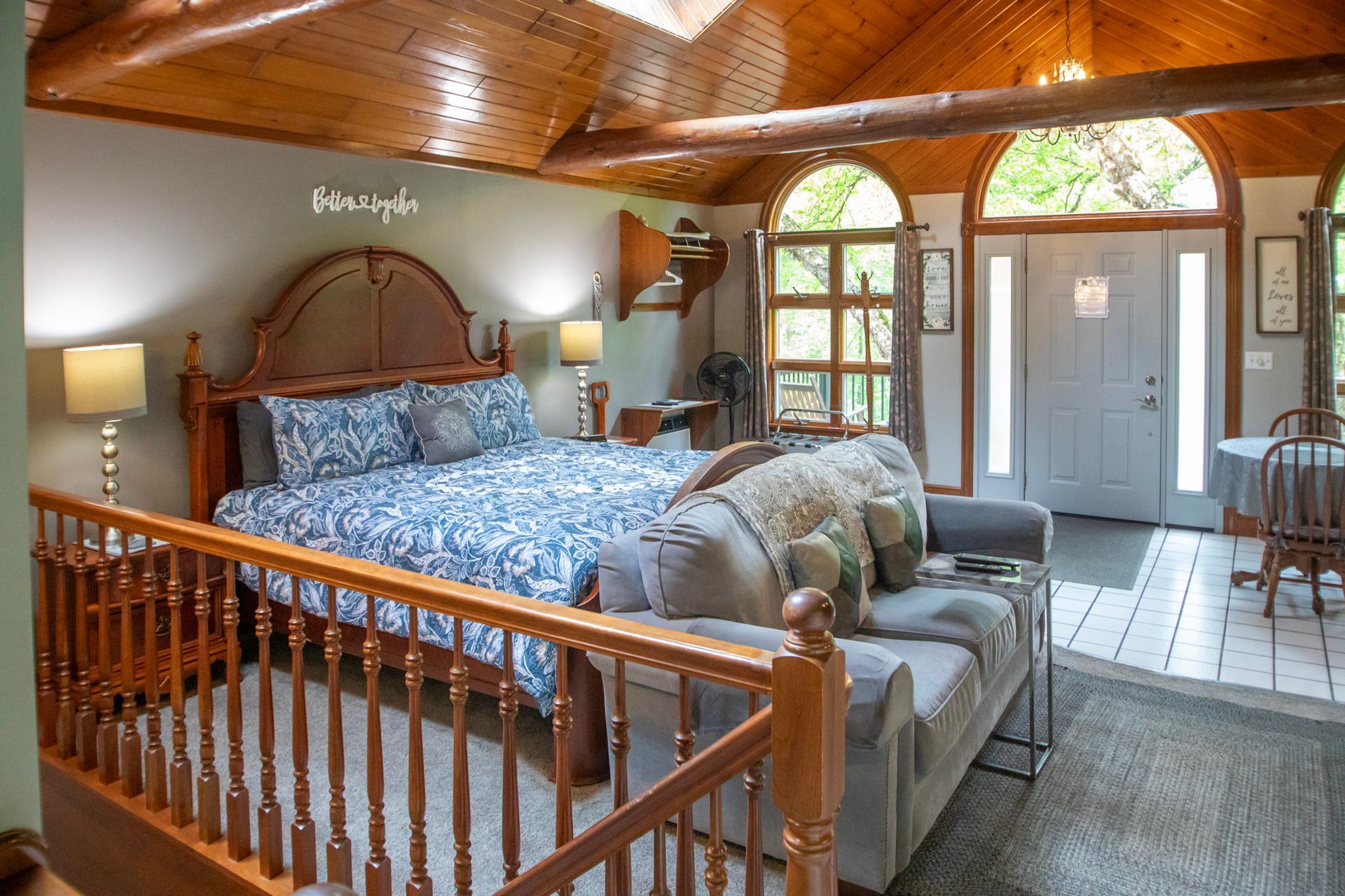 Bedroom with a bed, sofa, and a door, with wood accents and natural light.