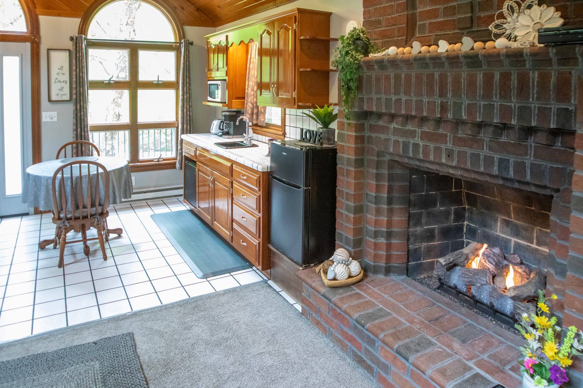 Cozy kitchen with a fireplace. Includes a round table, cabinetry, and a black refrigerator.