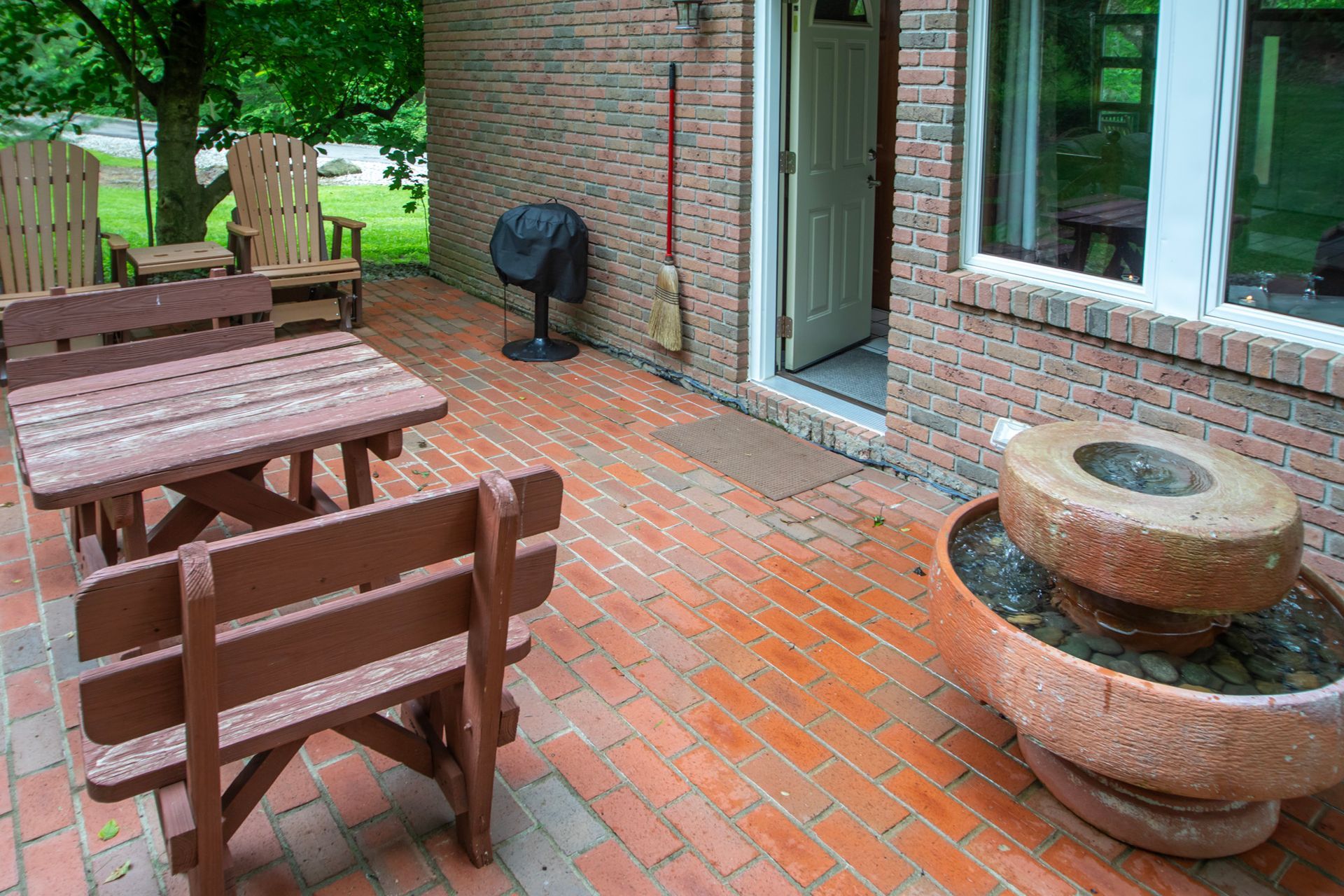Brick patio with picnic tables, benches, a grill, and a decorative stone planter.