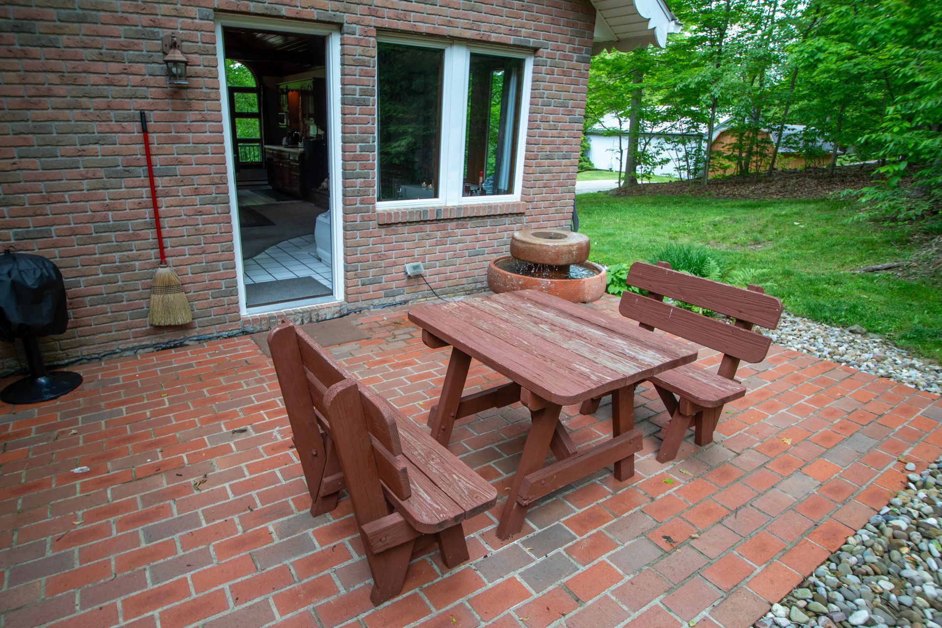 Red brick patio with picnic table and benches next to a brick building.