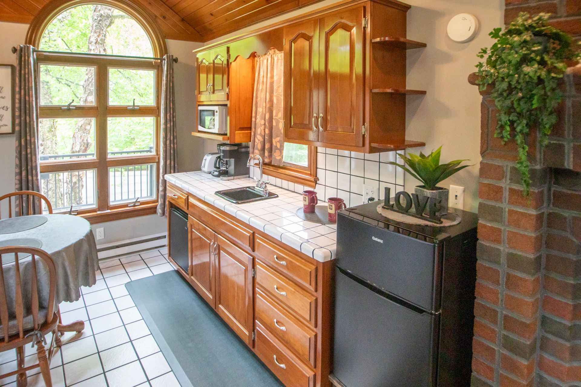 Kitchen with wooden cabinets, a round table, and a black refrigerator.