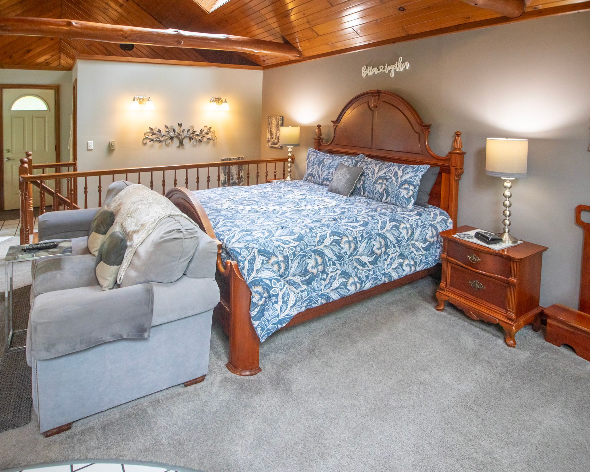 Bedroom with a wood bed, nightstand, sofa, and a loft area with a wood ceiling and carpet.