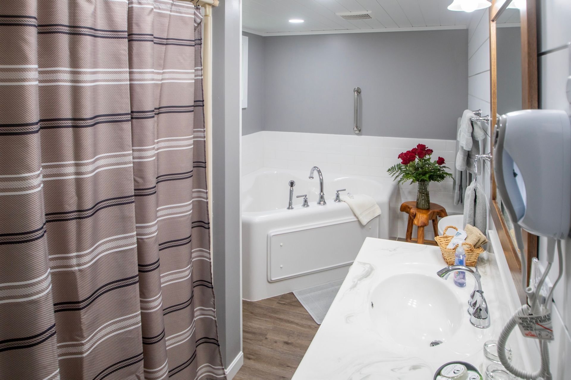 Bathroom with a white bathtub, vanity, and a striped shower curtain.