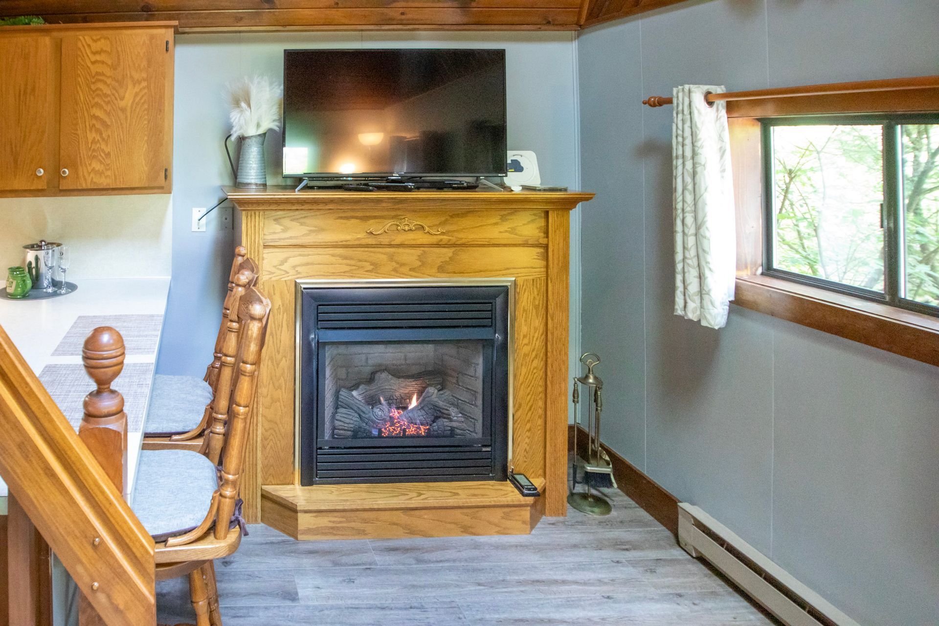 Cozy living space with a fireplace, TV, small window, and light wooden accents.